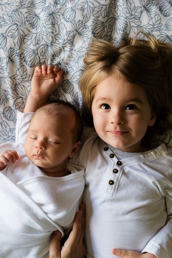 A child and a baby laying in a bed
